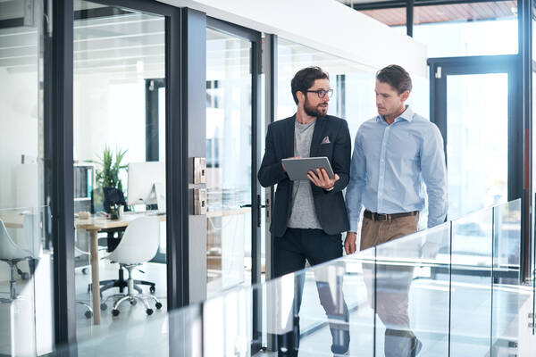image of two people working in an office, talking over something on an ipad