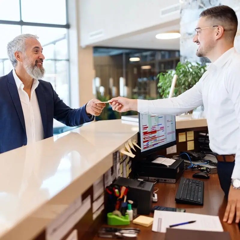 receptionist at hotel giving room key to customer
